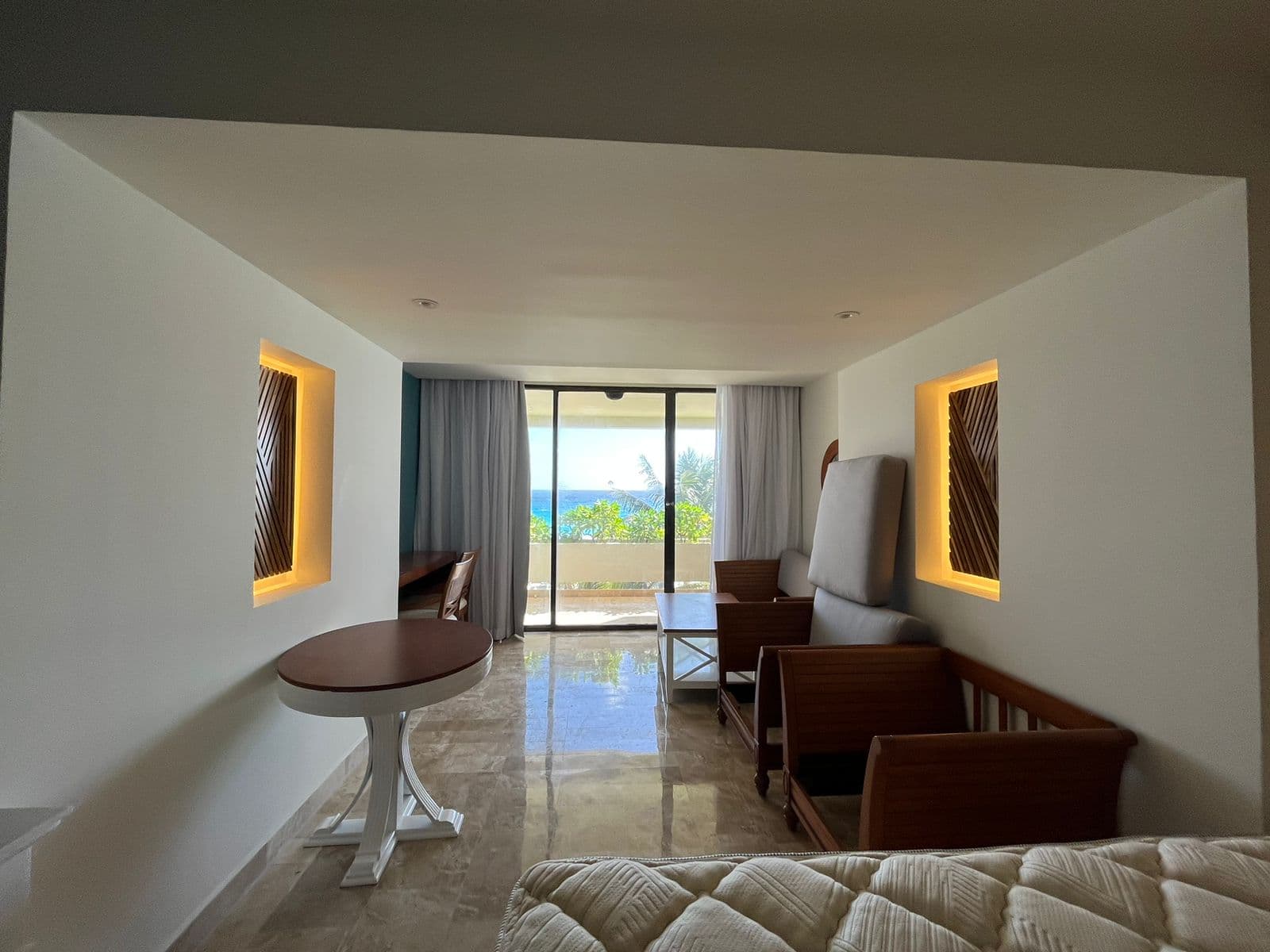 Interior de habitación — paneles retroiluminados simétricos, vista al océano desde el balcón