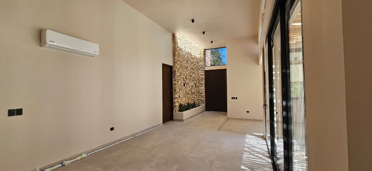 Casa Juuba — interior principal, volumen de doble altura y muro de piedra